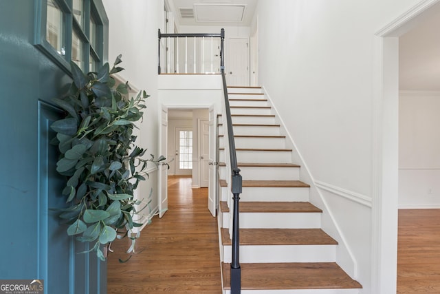 stairs with visible vents, a high ceiling, and wood finished floors