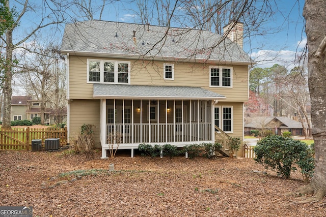 back of house featuring fence, roof with shingles, central AC unit, a chimney, and a sunroom