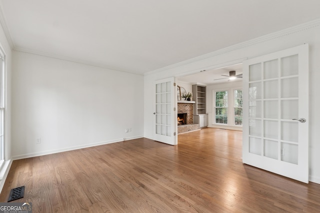 unfurnished living room with visible vents, ornamental molding, and wood finished floors