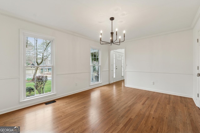 unfurnished dining area featuring visible vents, ornamental molding, wood finished floors, baseboards, and a chandelier