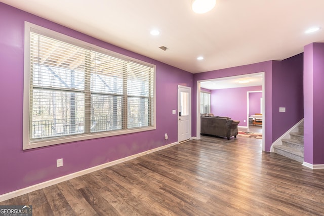 spare room with stairway, visible vents, baseboards, and wood finished floors