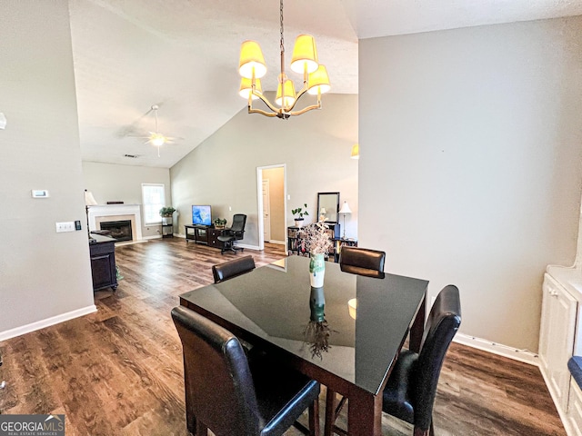 dining area with vaulted ceiling, ceiling fan with notable chandelier, a fireplace, and wood finished floors