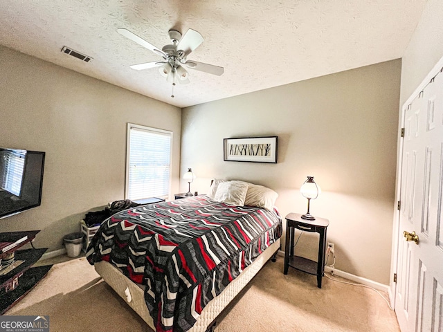 bedroom with visible vents, a textured ceiling, carpet floors, baseboards, and ceiling fan