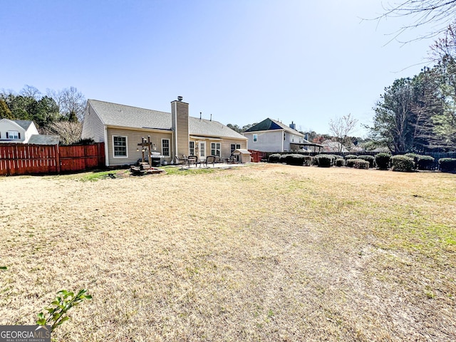 rear view of house with a patio, a yard, fence, and a chimney