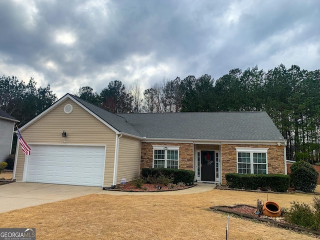 ranch-style home with a shingled roof, concrete driveway, a front yard, a garage, and stone siding