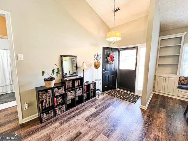 entryway with visible vents, baseboards, a textured ceiling, and wood finished floors