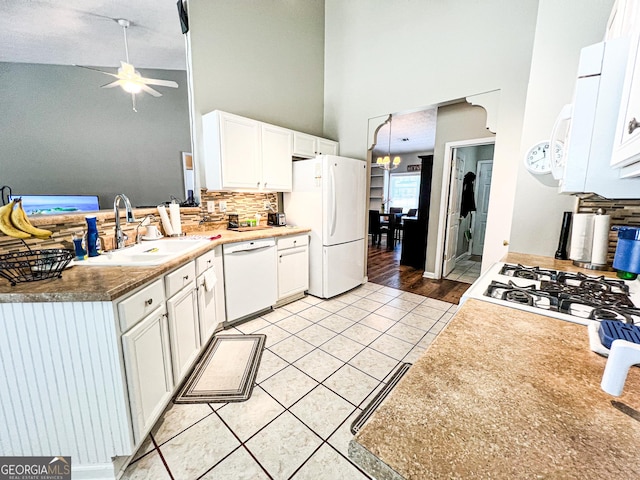 kitchen with white appliances, white cabinets, light tile patterned floors, and a sink