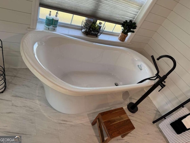 full bathroom with marble finish floor and a soaking tub