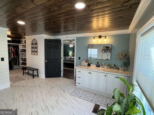 ensuite bathroom with connected bathroom, wooden ceiling, a spacious closet, crown molding, and vanity