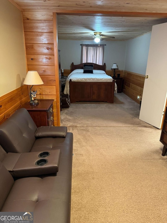 carpeted bedroom featuring wood walls, a ceiling fan, and wainscoting