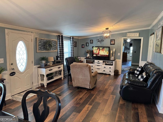 living area with a healthy amount of sunlight, dark wood-style floors, ornamental molding, and a chandelier