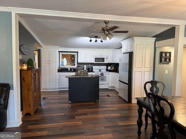 kitchen featuring white appliances, a kitchen island, ornamental molding, dark wood-style floors, and dark countertops