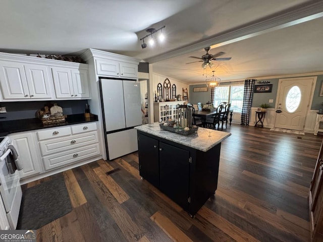 kitchen with stove, a kitchen island, white cabinets, freestanding refrigerator, and dark wood-style floors