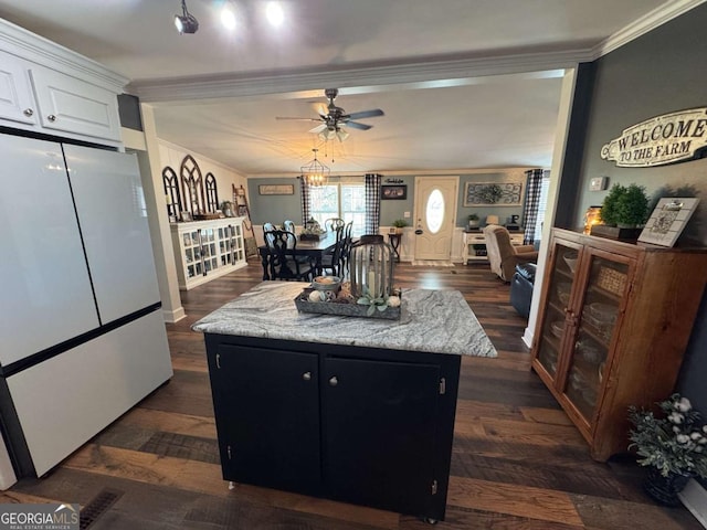 kitchen with a kitchen island, dark wood-type flooring, freestanding refrigerator, crown molding, and white cabinetry