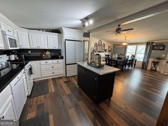 kitchen featuring white appliances, dark wood-style flooring, a kitchen island, white cabinetry, and ornamental molding