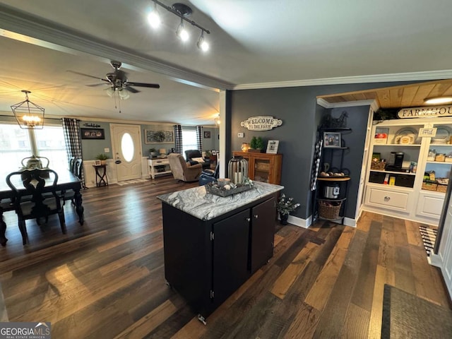 interior space with crown molding, a kitchen island, dark cabinetry, and dark wood-type flooring