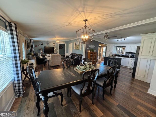 dining space with ceiling fan with notable chandelier, dark wood finished floors, and crown molding