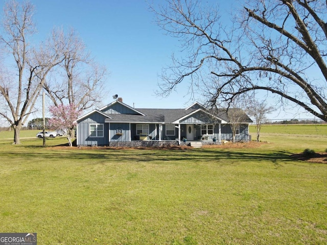 rear view of house featuring covered porch, a lawn, and board and batten siding