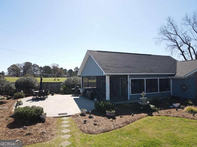 rear view of property with a shingled roof, a lawn, a sunroom, fence, and a patio area