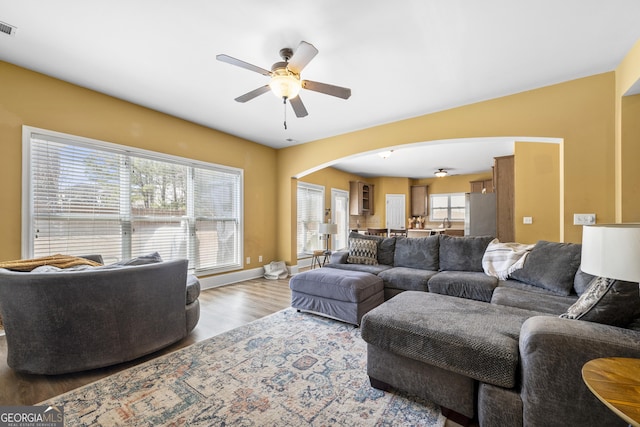 living area with baseboards, visible vents, arched walkways, ceiling fan, and wood finished floors