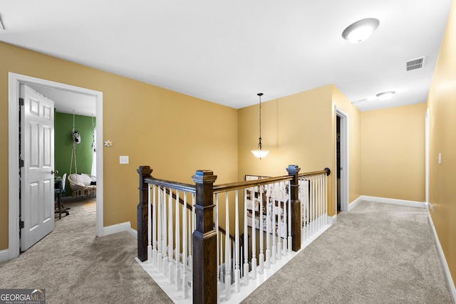 hall featuring baseboards, visible vents, carpet floors, and an upstairs landing