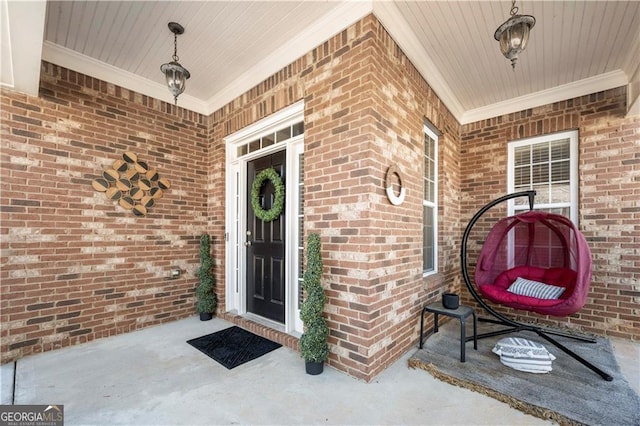 view of exterior entry with brick siding and covered porch