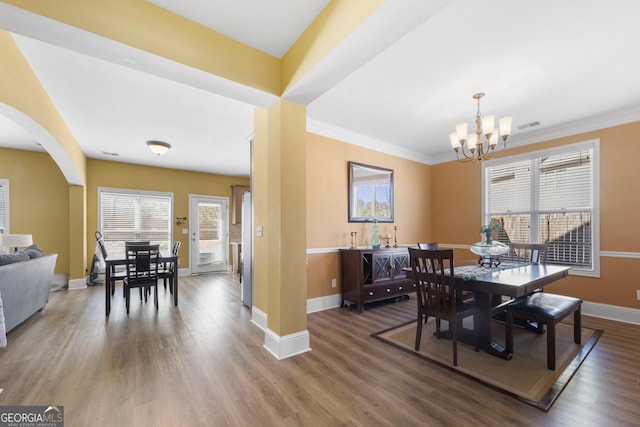 dining space with arched walkways, wood finished floors, visible vents, baseboards, and an inviting chandelier