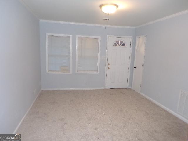 entrance foyer with light carpet, ornamental molding, visible vents, and baseboards