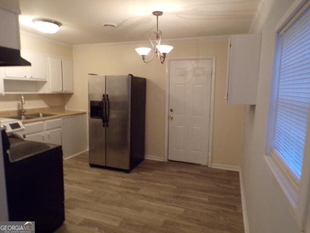 kitchen featuring wood finished floors, an inviting chandelier, stainless steel fridge, and white cabinets