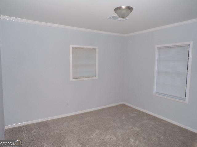 carpeted spare room with baseboards and crown molding