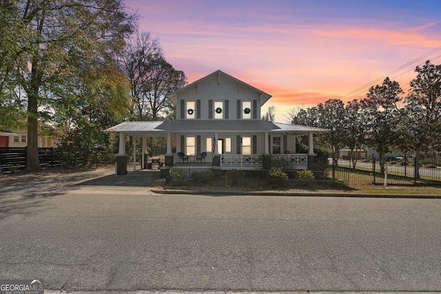 farmhouse inspired home featuring metal roof, a porch, fence, and an attached carport