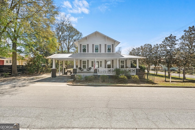 farmhouse with an attached carport, covered porch, fence, and driveway