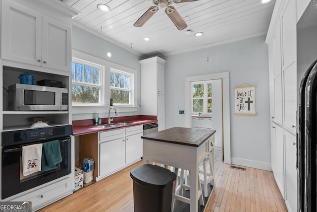 kitchen with crown molding, light wood-style floors, a sink, and black appliances