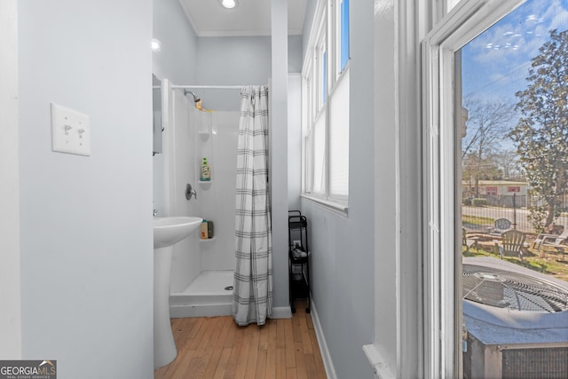 bathroom with curtained shower, wood-type flooring, and baseboards