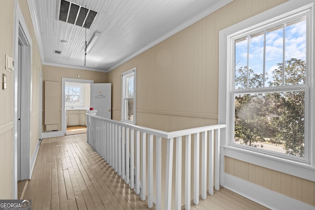 corridor with light wood finished floors and ornamental molding