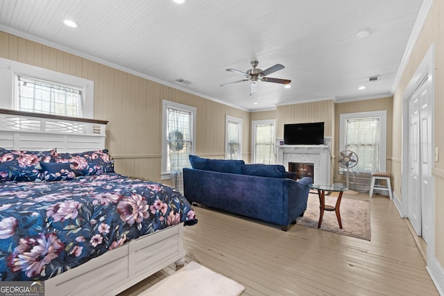 bedroom featuring wood-type flooring, a fireplace, visible vents, and crown molding