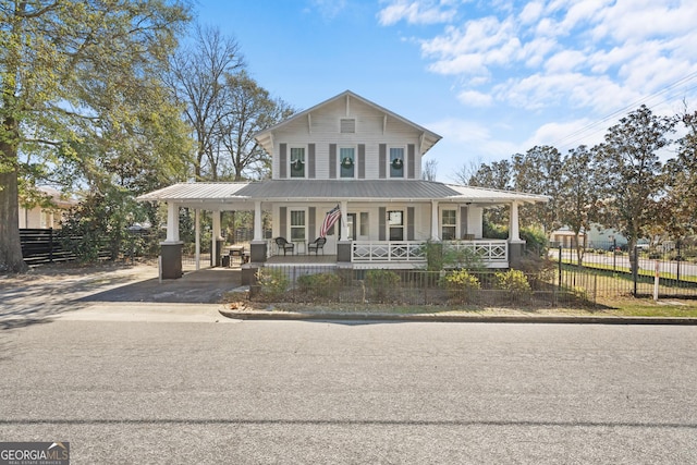 farmhouse inspired home featuring metal roof, a fenced front yard, covered porch, driveway, and a carport