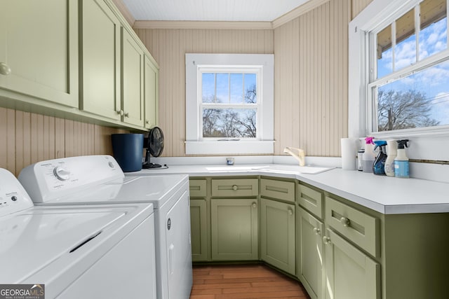 laundry area with cabinet space, independent washer and dryer, crown molding, light wood-style floors, and a sink