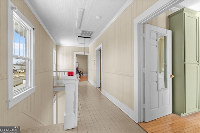 hallway with light wood-type flooring, visible vents, and crown molding