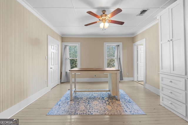 unfurnished office featuring ceiling fan, visible vents, baseboards, light wood-style floors, and ornamental molding