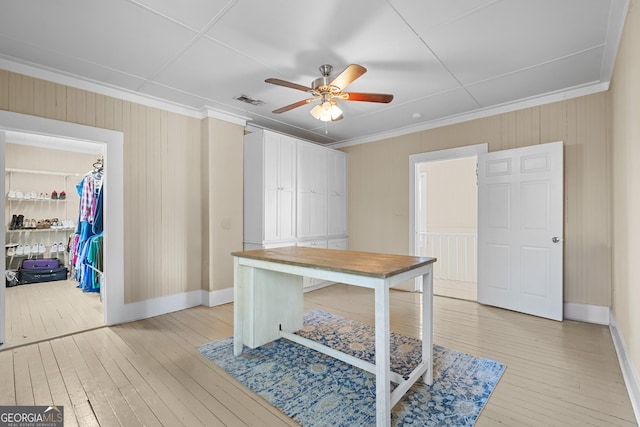 home office featuring light wood-style floors, visible vents, ornamental molding, and a ceiling fan