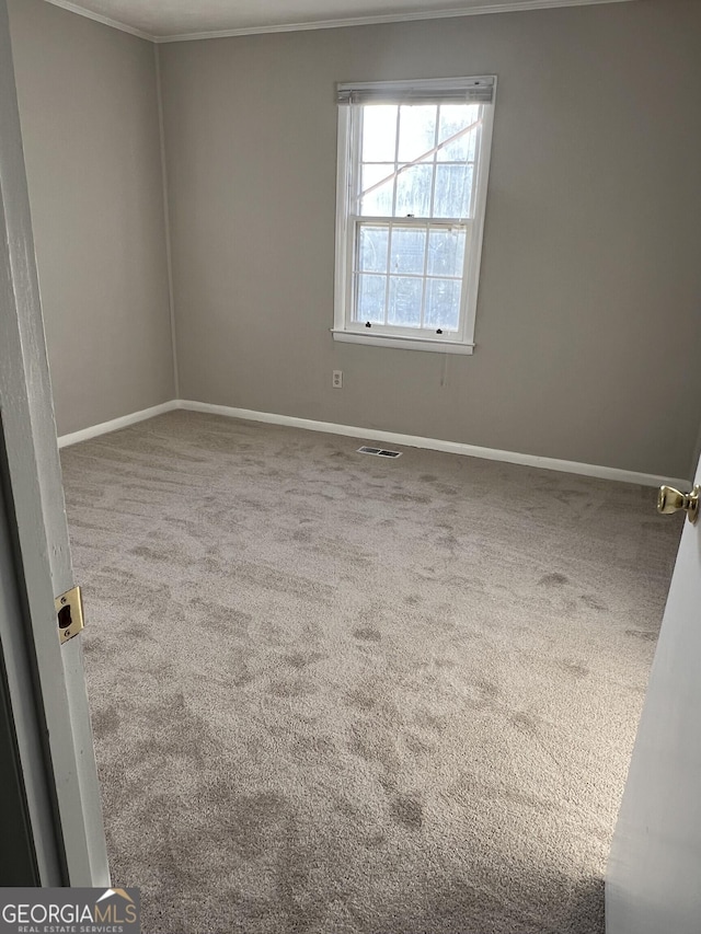 carpeted empty room featuring baseboards, visible vents, and crown molding