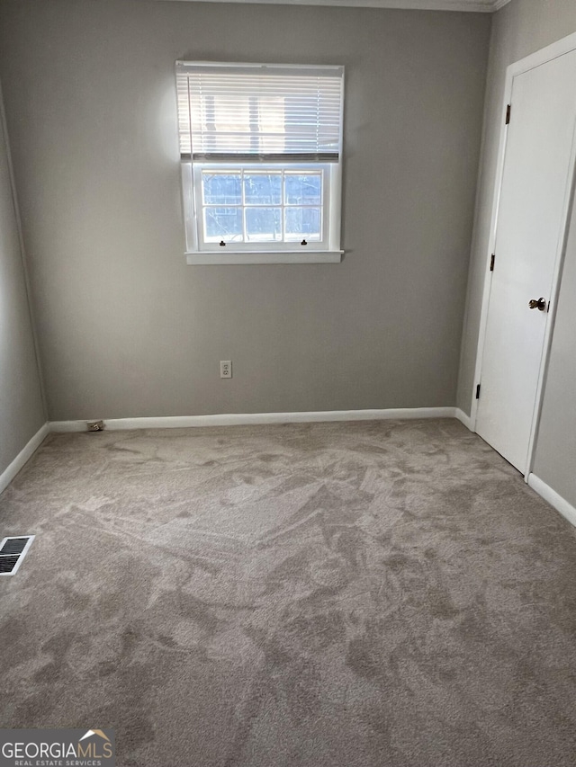 carpeted empty room with visible vents and baseboards