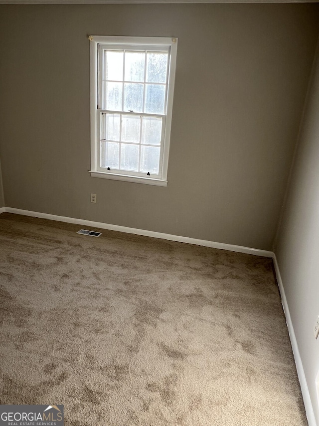 empty room featuring baseboards, visible vents, and carpet flooring