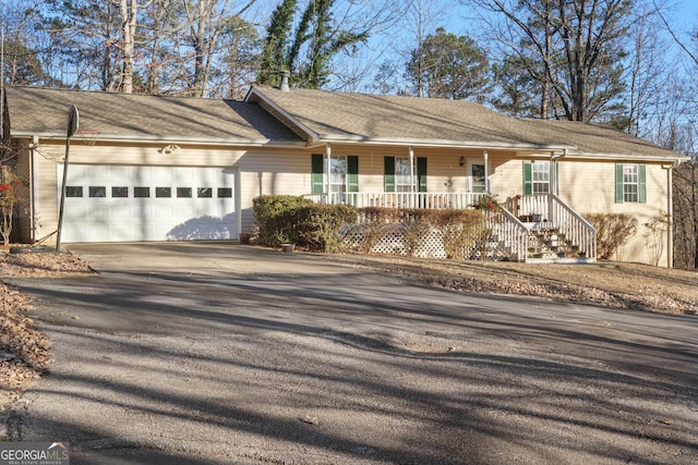 single story home featuring driveway, a porch, and an attached garage