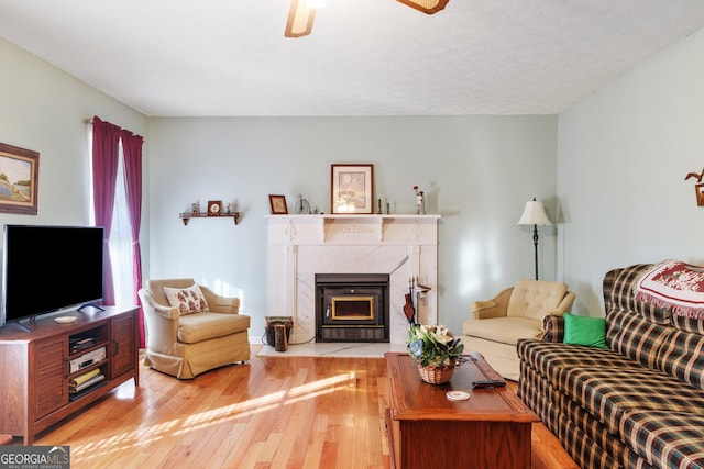 living room with light wood-style flooring, a fireplace, and ceiling fan