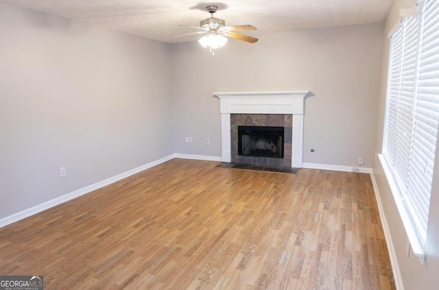 unfurnished living room with a ceiling fan, light wood-type flooring, a fireplace, and baseboards