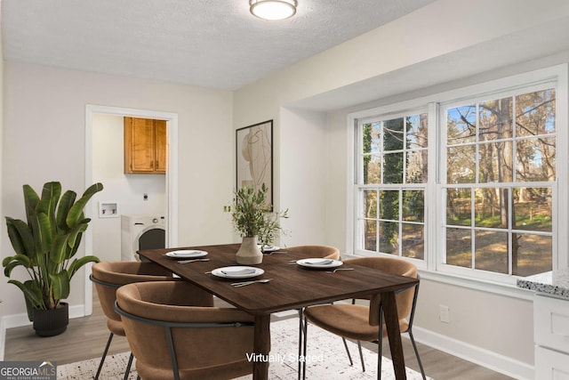 dining room with washer / dryer, a textured ceiling, a wealth of natural light, and light wood-style floors