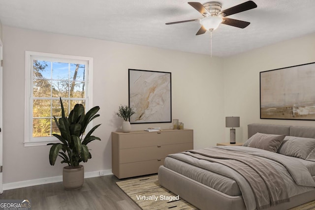 bedroom with ceiling fan, a textured ceiling, baseboards, and wood finished floors