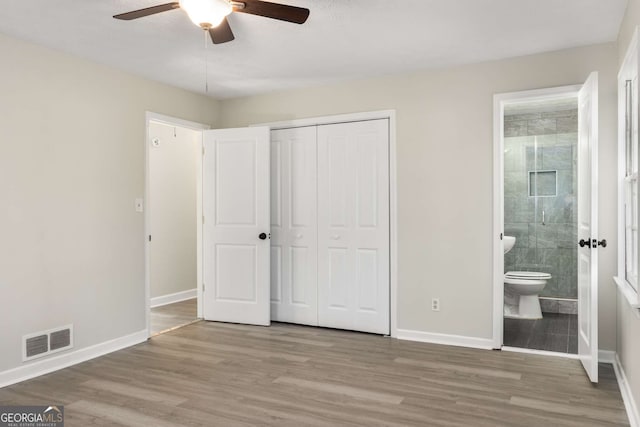 unfurnished bedroom with a closet, visible vents, baseboards, and wood finished floors